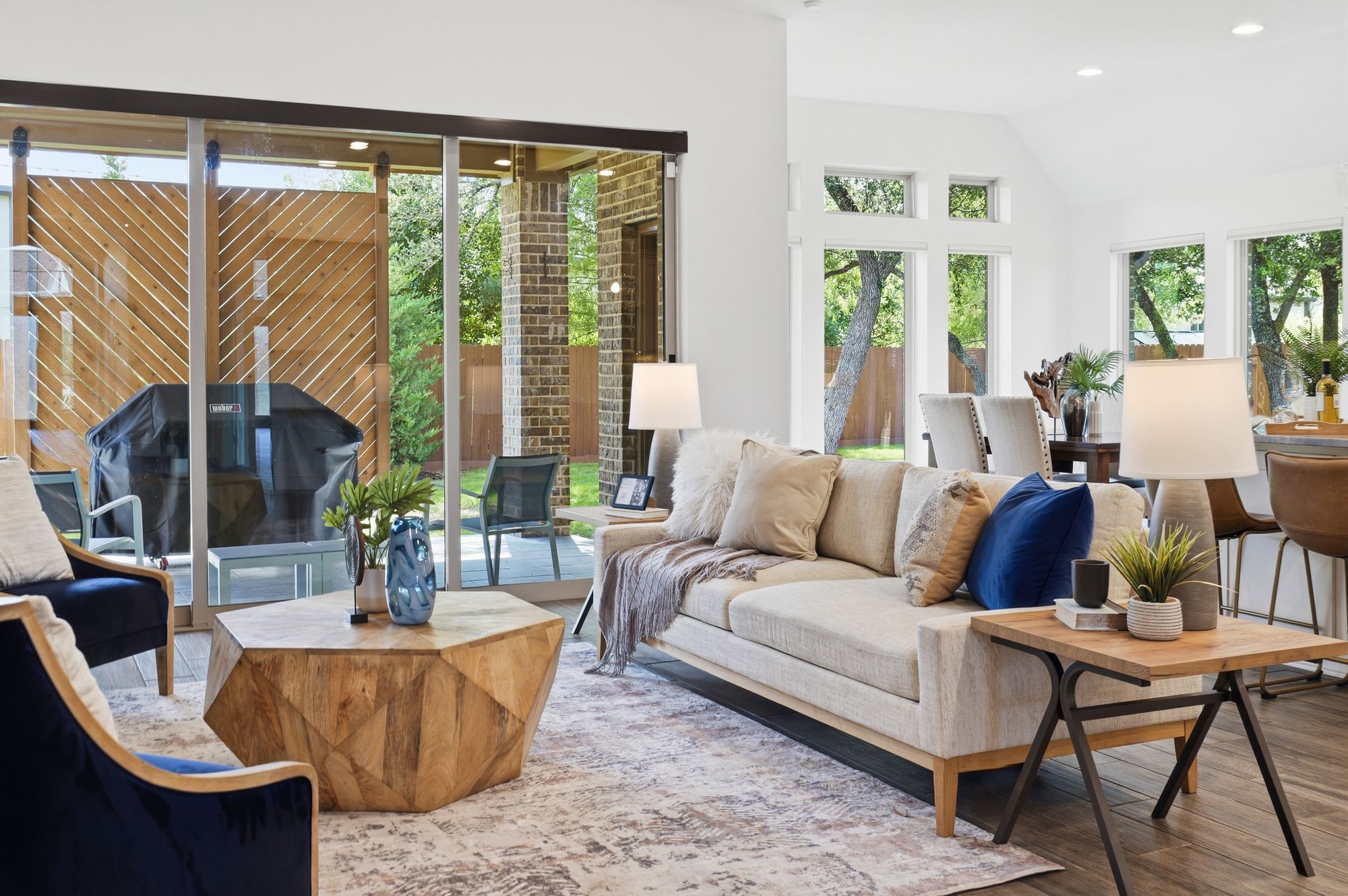 Living room open through the triple sliding glass wall to the covered patio