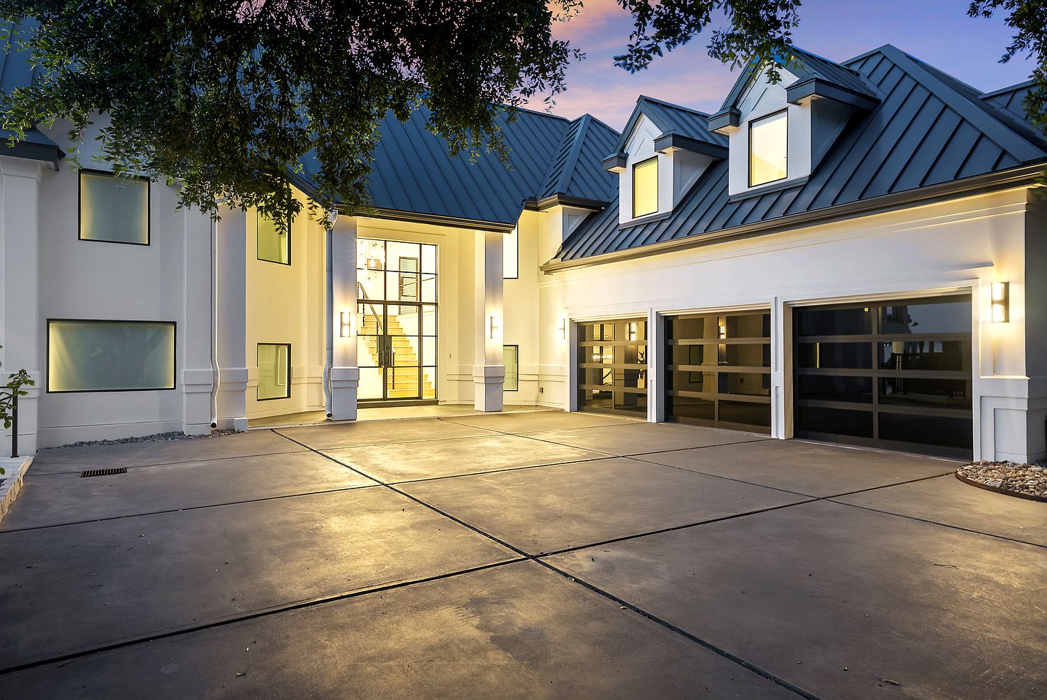 Three-car glass garage and motor court with two-story glass entry