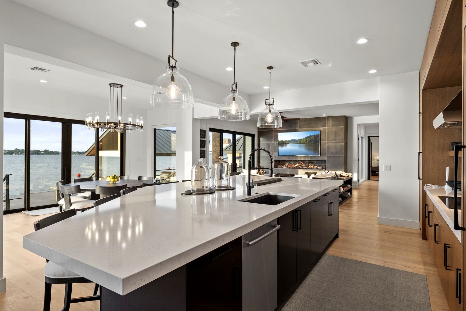 Kitchen with oversized waterfall-edge stone island, glass dome pendants and lake views