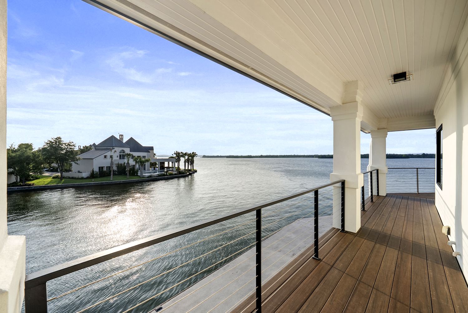 Covered terrace with V-groove ceiling and cable railing over the water